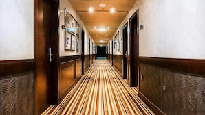 A hotel hallway with wooden doors, framed pictures, and a striped carpet. - Hotel Granda (Cangas de Onís)
