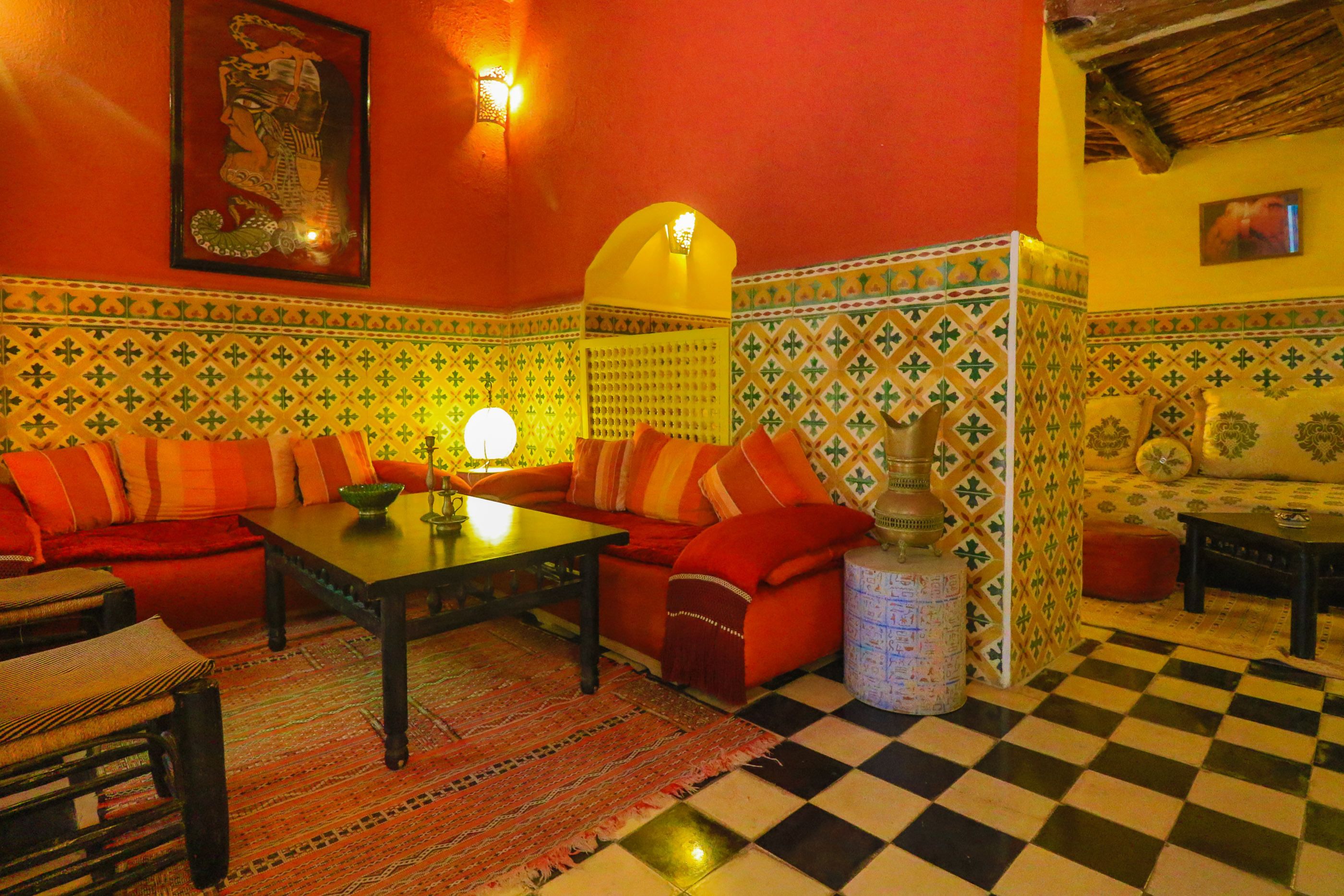Un salon chaleureux avec un sol à carreaux, un ensemble de canapés, une table basse et un mur décoré d’un motif.