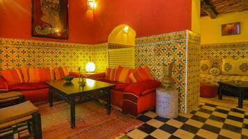 Un salon chaleureux avec un sol à carreaux, un ensemble de canapés, une table basse et un mur décoré d’un motif.