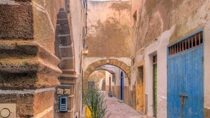 A narrow cobblestone street with a yellow planter, a blue door, and an arched passageway. - Les Matins Bleus (Essaouira)