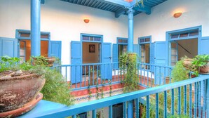 A courtyard with blue railings, potted plants, and a tiled floor. - Les Matins Bleus (Essaouira)