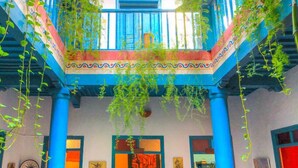 A courtyard with a checkered floor, blue columns, and hanging plants. - Les Matins Bleus (Essaouira)