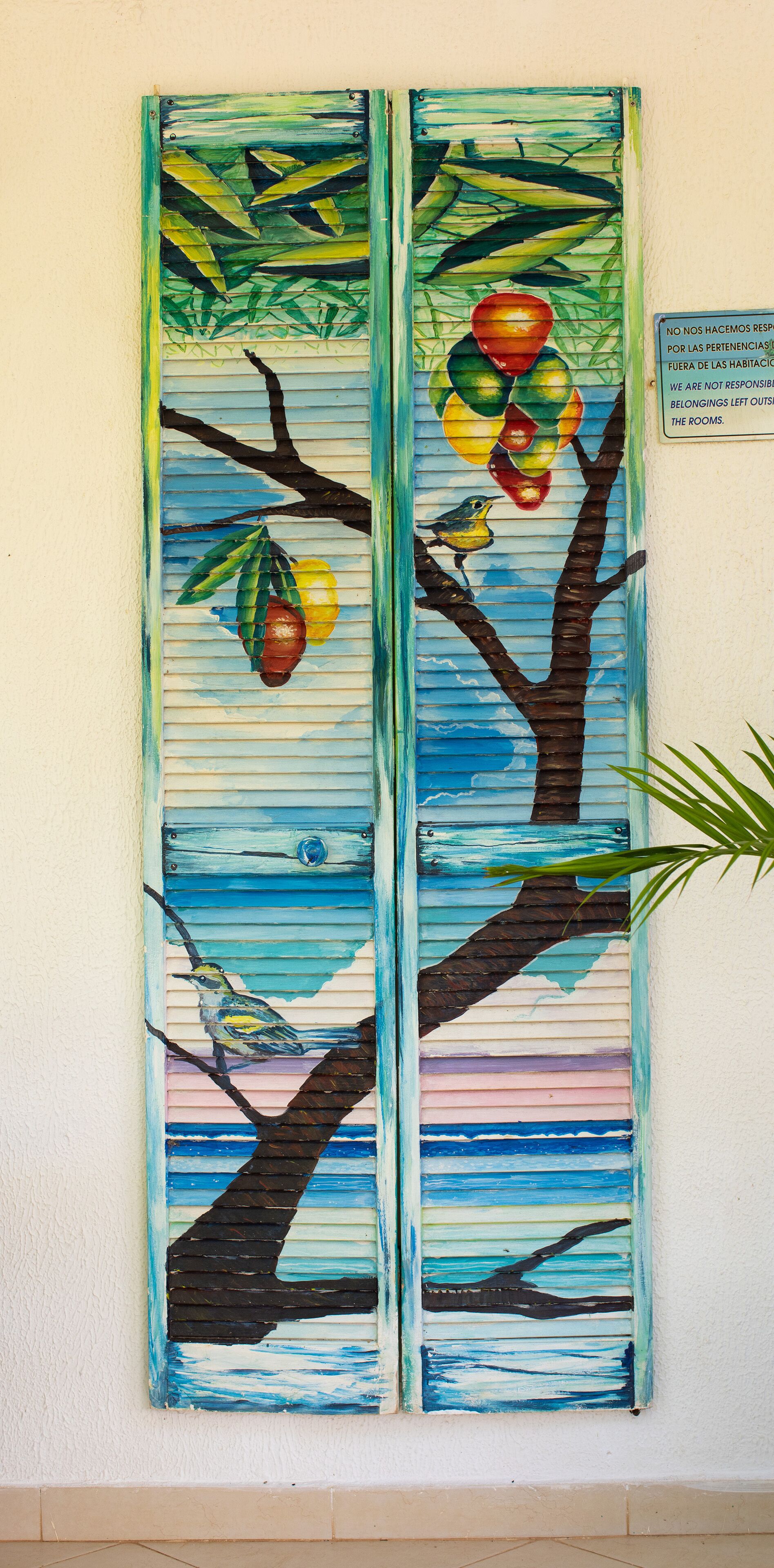 A wall with two vertical panels depicting tropical scenes with birds and fruit.
