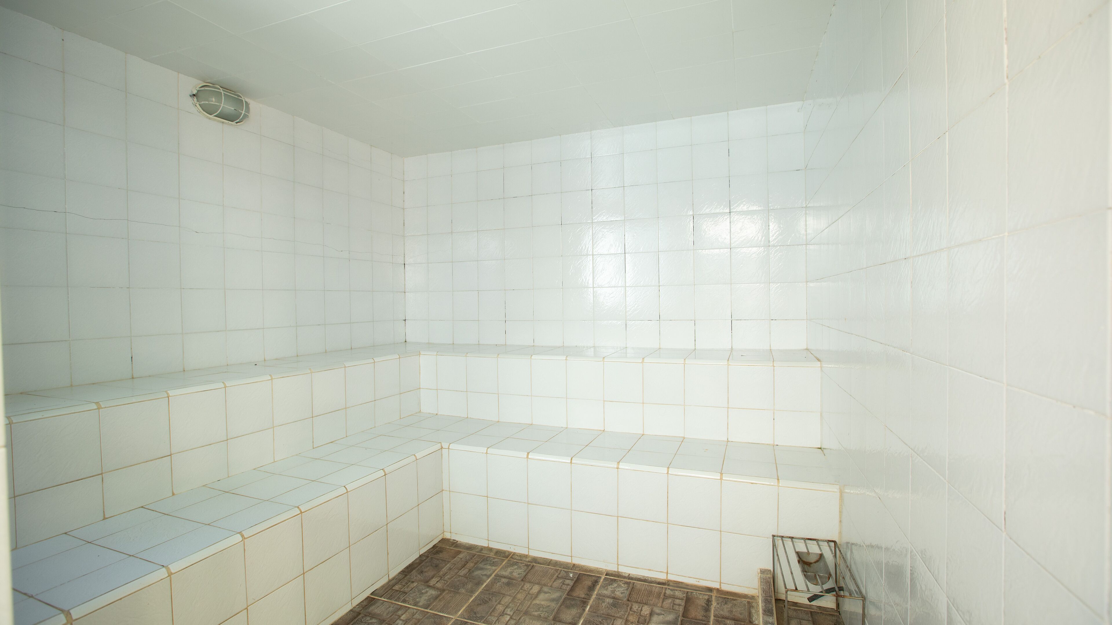 Un baño con paredes de azulejos blancos y suelo de madera.