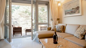 A modern living room with a sofa, a table with a bottle and glasses, and a balcony with chairs. - Dariusz Apartament PREMIUM Jurata z garażem (Jurata)