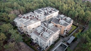 A modern multi-story residential building with a rooftop terrace and a view of a dense forest. - Dariusz Apartament PREMIUM Jurata z garażem (Jurata)