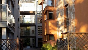 A modern urban courtyard with a wooden pathway, metal fences, and a mix of residential buildings with balconies and large windows. - Dariusz Apartament PREMIUM Jurata z garażem (Jurata)