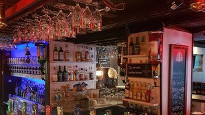 A bar area with multiple liquor bottles, glasses, and a beer tap. - Hotell Kong Christian (Kristianstad)