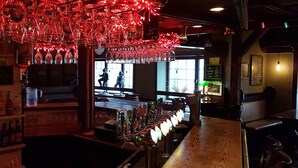 A bar area with a wooden counter and a red light fixture above it. - Hotell Kong Christian (Kristianstad)
