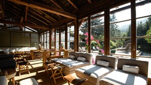 A spacious room with large windows, wooden beams, and a sofa area with cushions. - House of Hütter - Wachtelhof Hotel & Spa (Maria Alm am Steinernen Meer)