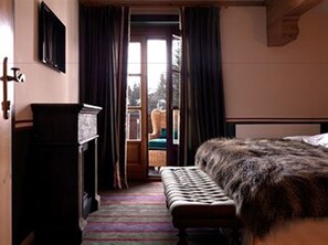 A bedroom with a bed, a bench, a dresser, and a window with curtains.