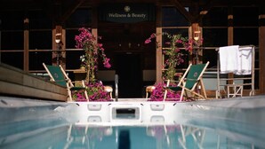 A pool area with lounge chairs and a sign reading "Wellness & Beauty". - House of Hütter - Wachtelhof Hotel & Spa (Maria Alm am Steinernen Meer)