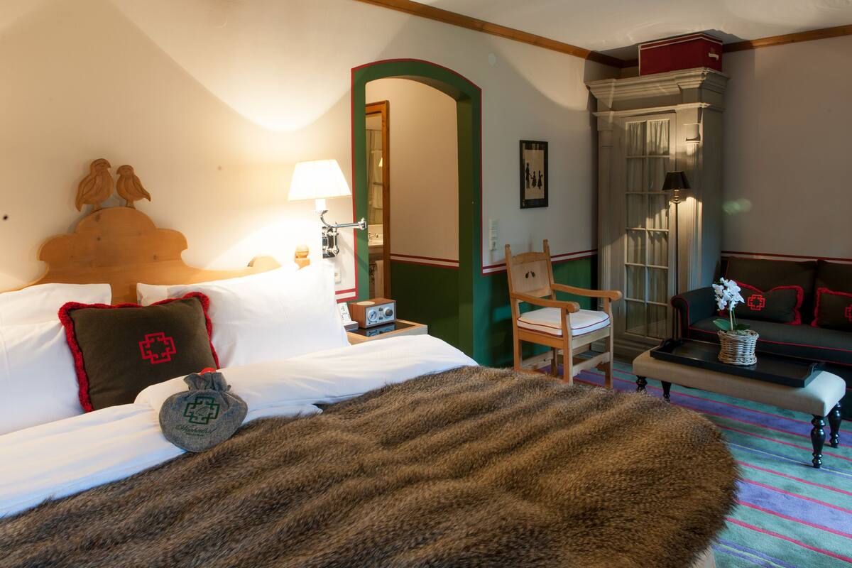 Et hotelværelse med seng, stol, sofa, bord og spejl.