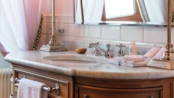 A bathroom with a marble sink, two black lamps, a mirror, and a window with white curtains.