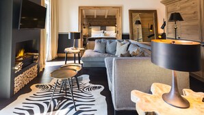 A modern living room with a fireplace, a sofa, a coffee table, and a TV mounted on the wall. - House of Hütter - Wachtelhof Hotel & Spa (Maria Alm am Steinernen Meer)