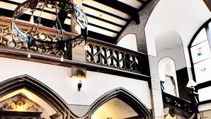 Un intérieur somptueux, avec un plafond haut, un escalier décoratif et une cheminée.