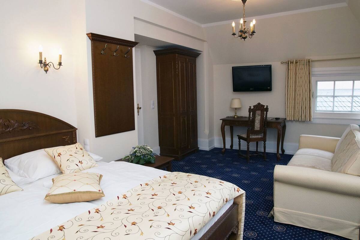Een hotelkamer met een bed, een bureau, een stoel, een televisie en een raam.