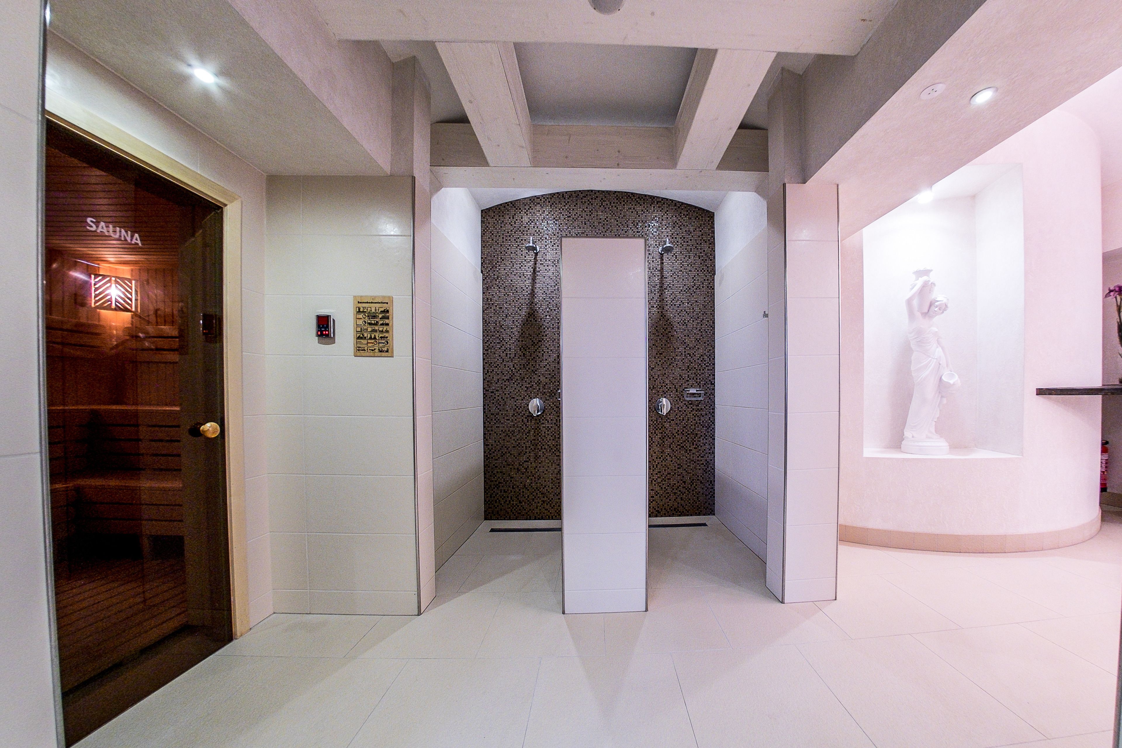 Un moderno espacio de spa con sauna, un pilar blanco grande y una estatua expuesta.