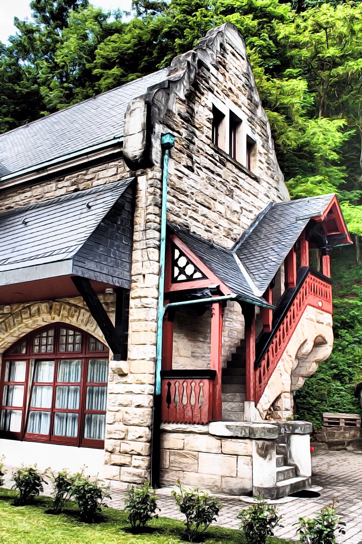 A stone building with a steep roof, red accents, and a stone staircase leading to a balcony.