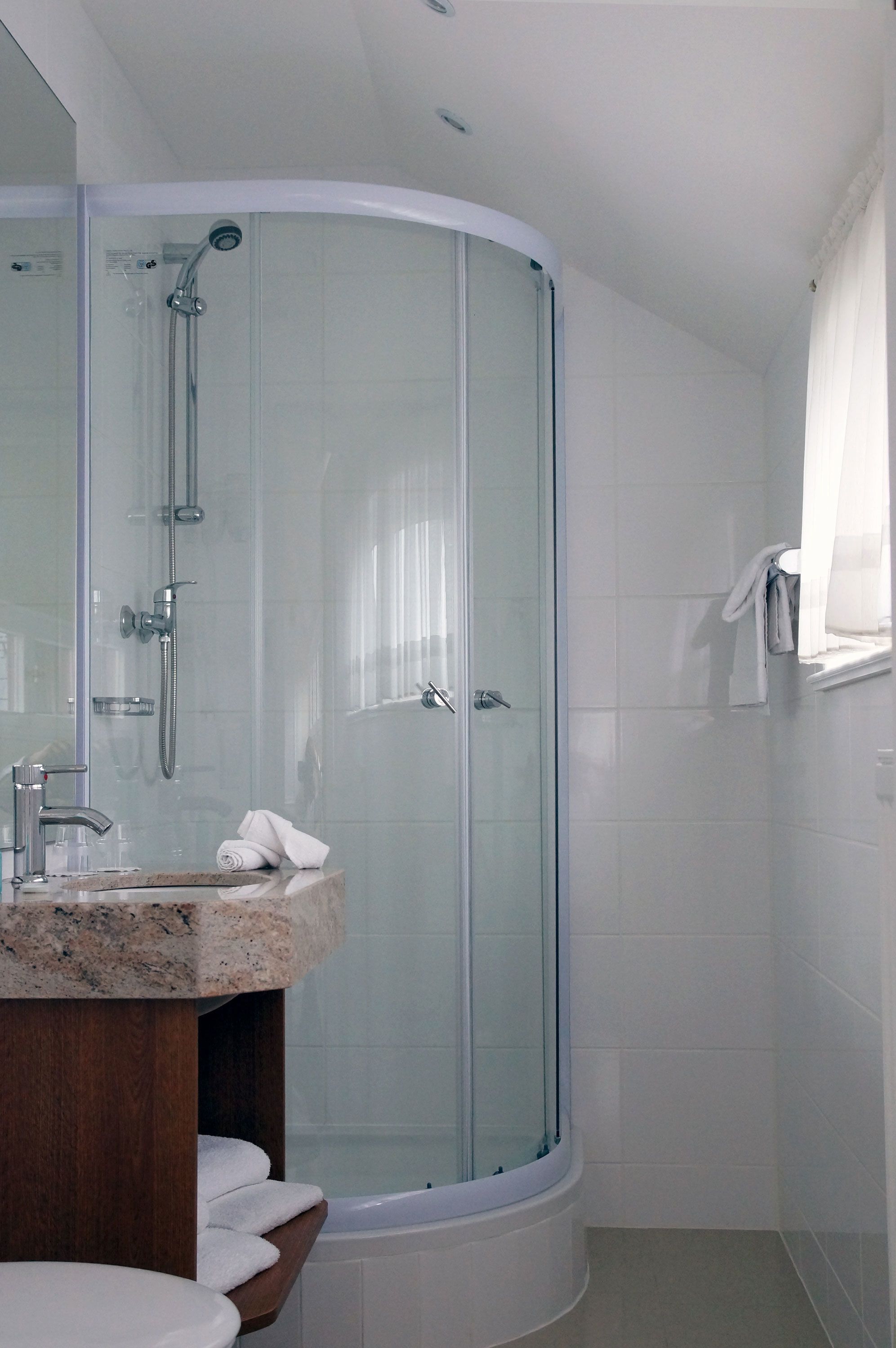 Un bagno moderno con doccia vetrata, lavabo in granito e mobile contenitore in legno.