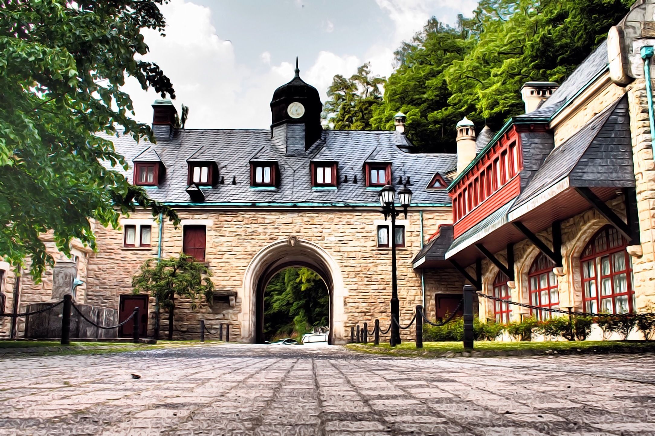A stone building with a clock tower, arched entrance, and red-framed windows.