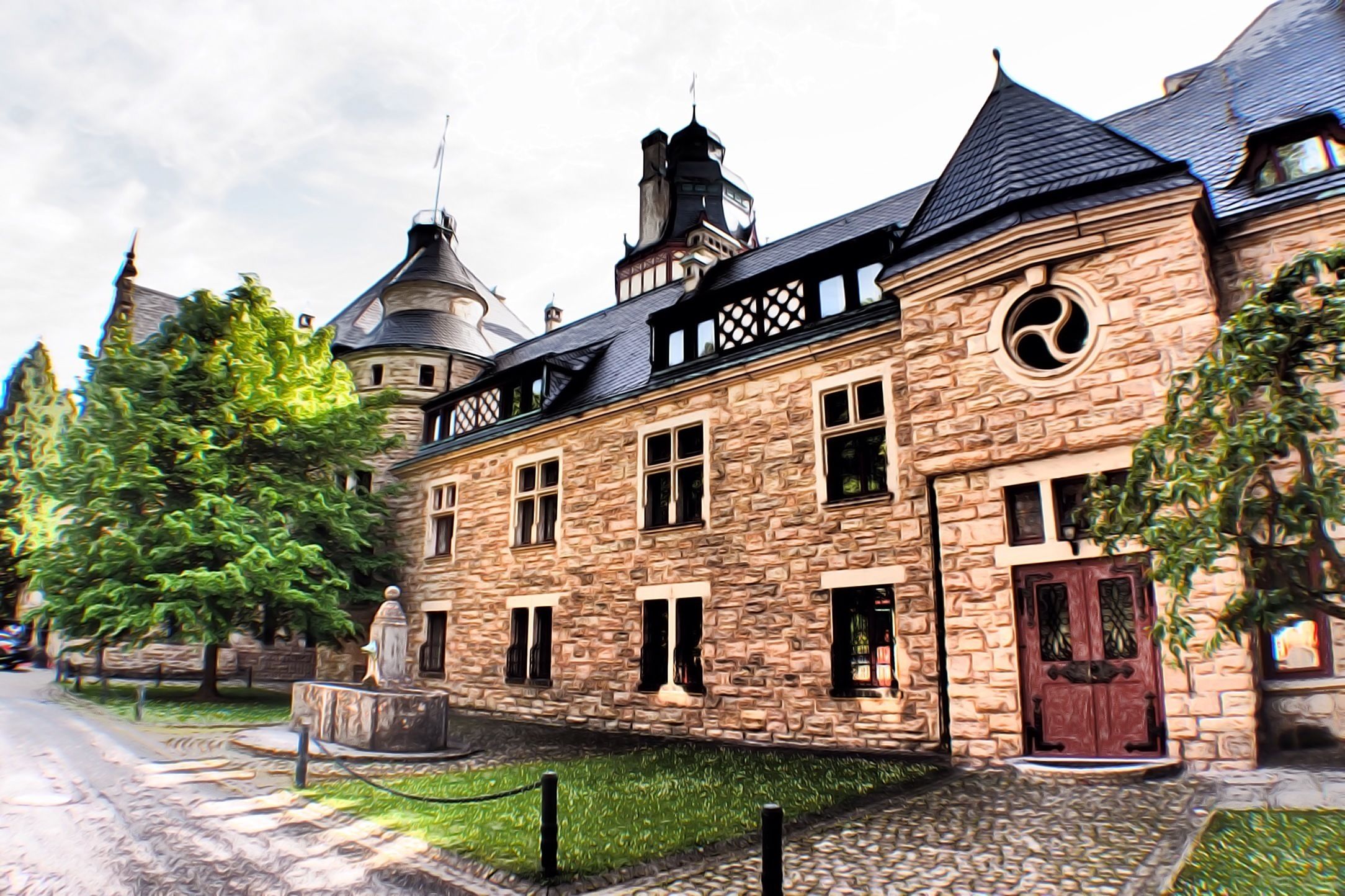 Un edificio histórico de piedra con una torre destacada, un patio central y una puerta de madera tradicional.