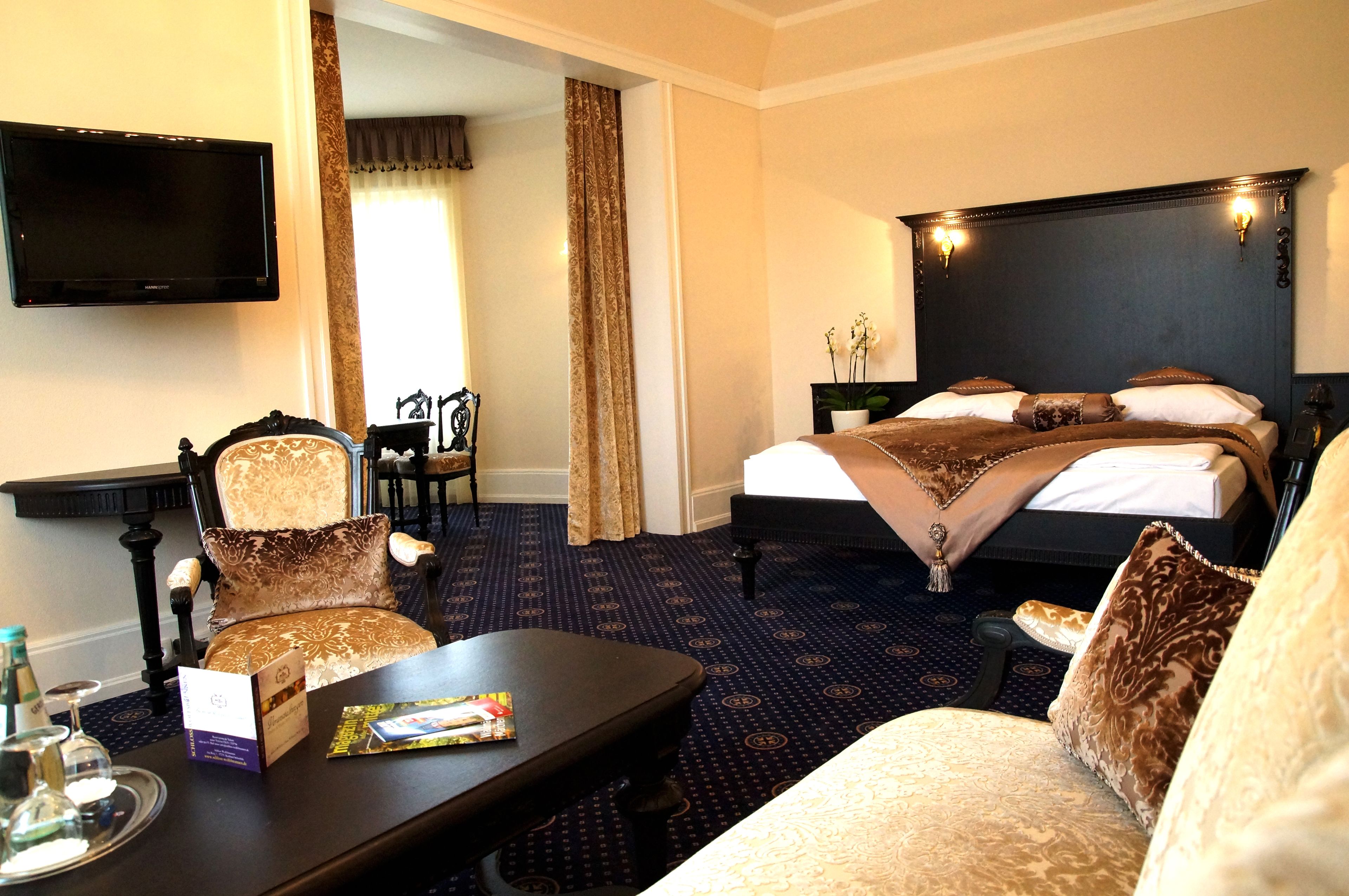 A hotel room with a bed, a desk, a chair, a television, and a window with curtains.