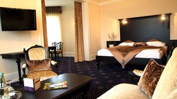 A hotel room with a bed, a desk, a chair, a television, and a window with curtains.