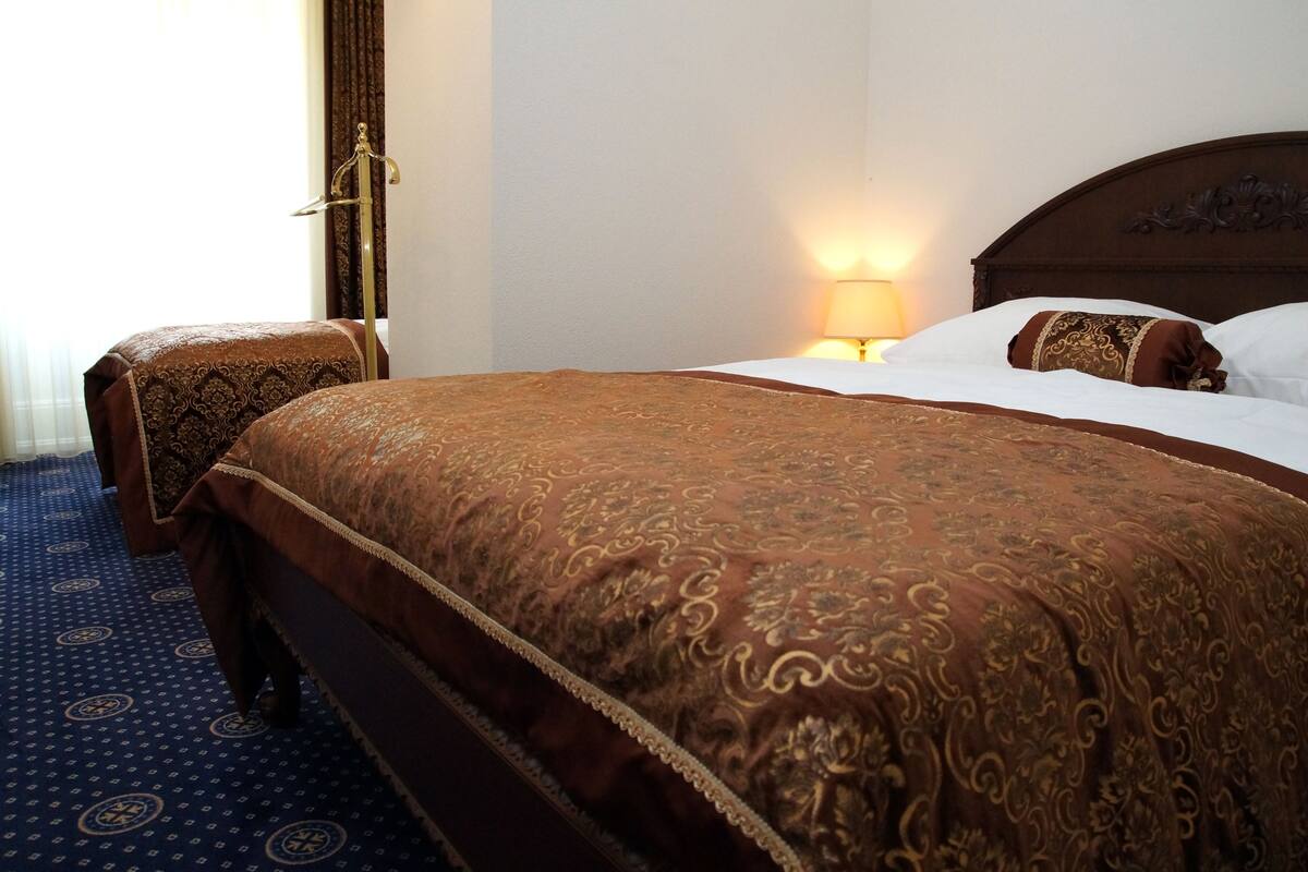 Een hotelkamer met een groot bed, een nachtkastje en een lamp.