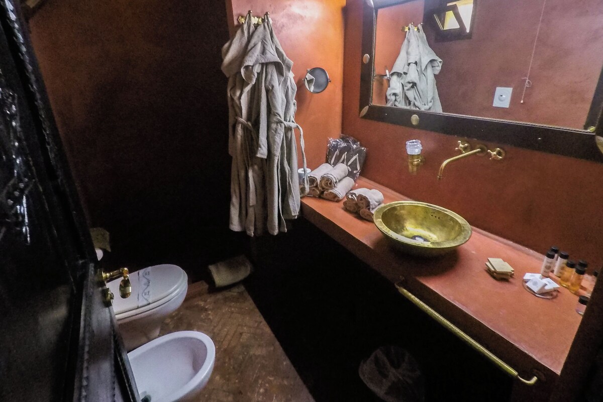 Un baño con lavamanos, espejo, toallero y retrete.