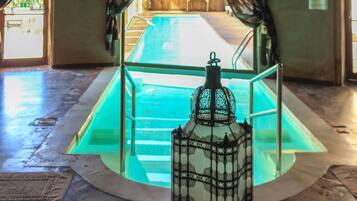 Une piscine intérieure avec un plafond en bois et des rideaux à motifs.