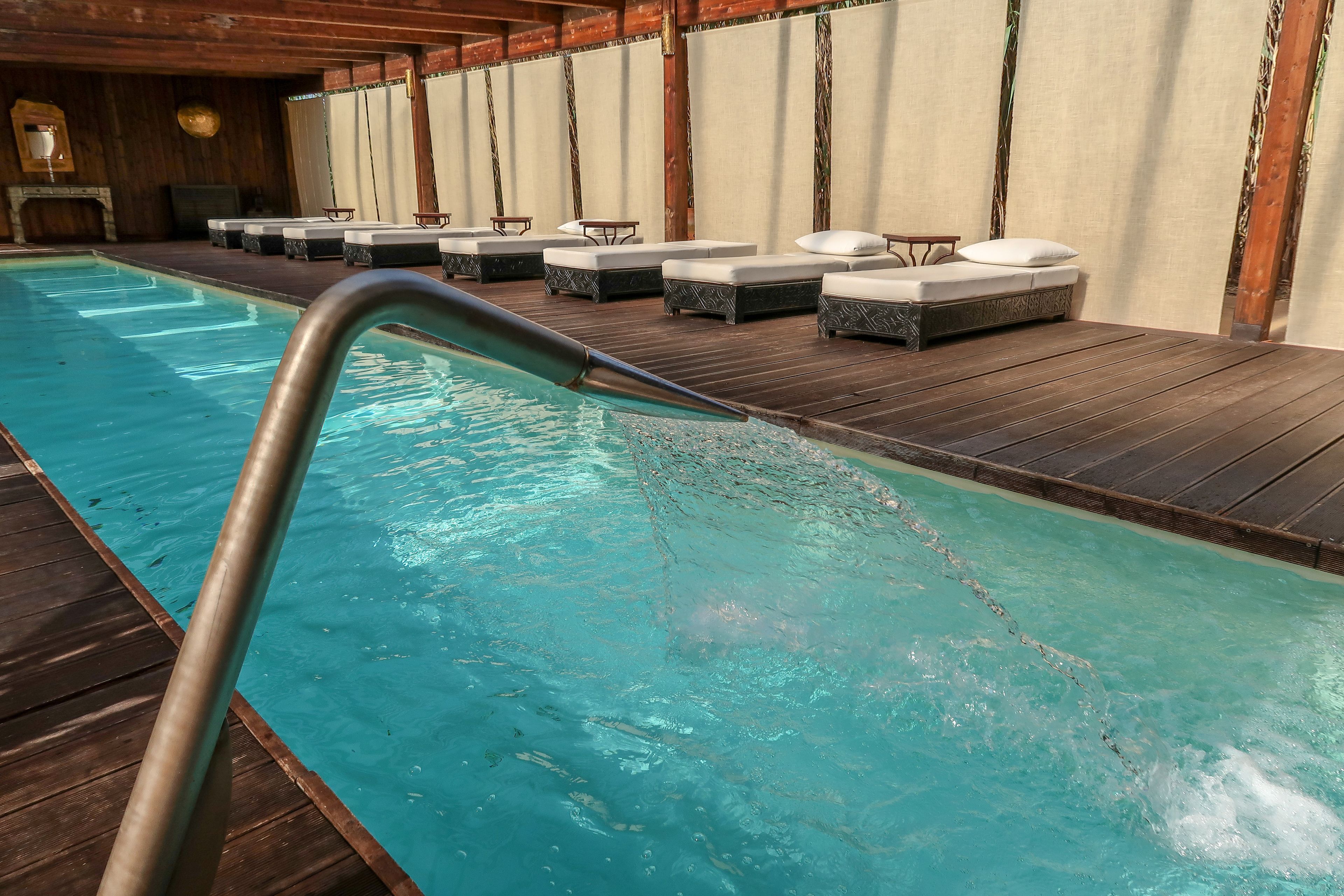 A pool area with wooden deck and lounge chairs.