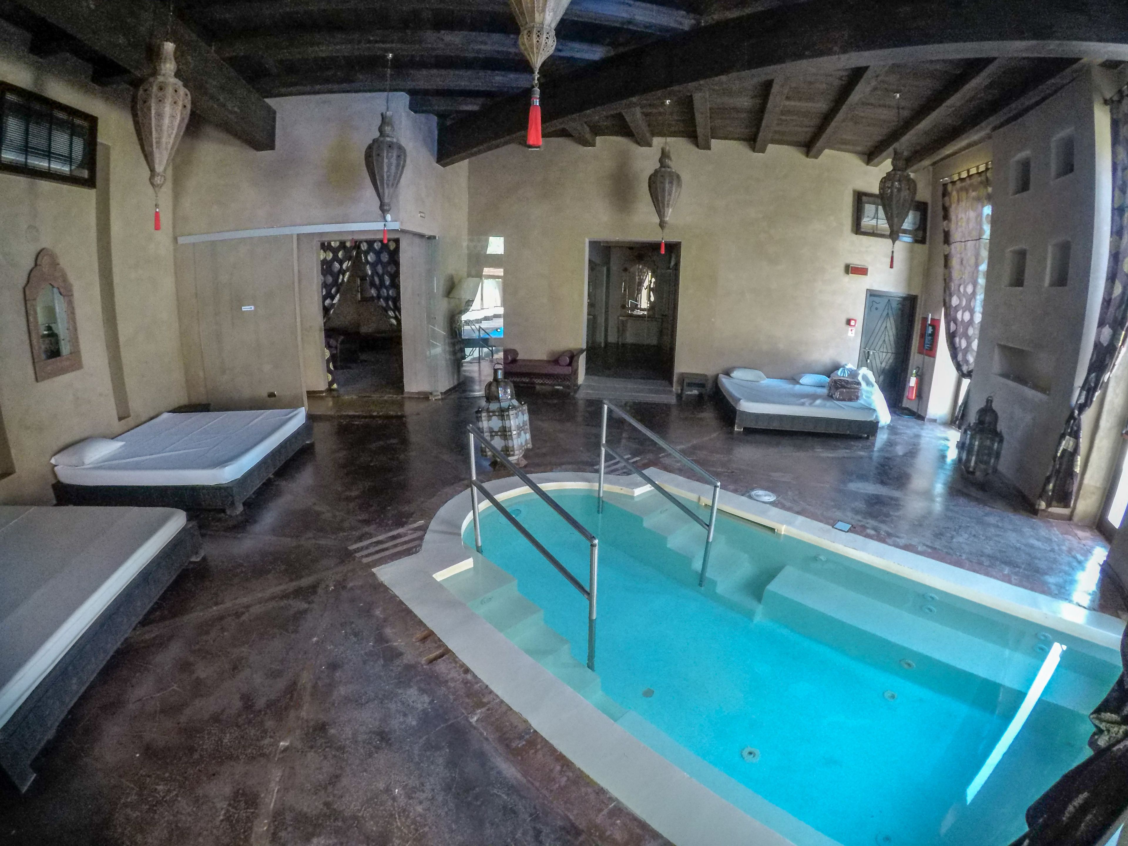 A pool area with a rectangular pool, benches, and a ceiling with exposed beams.