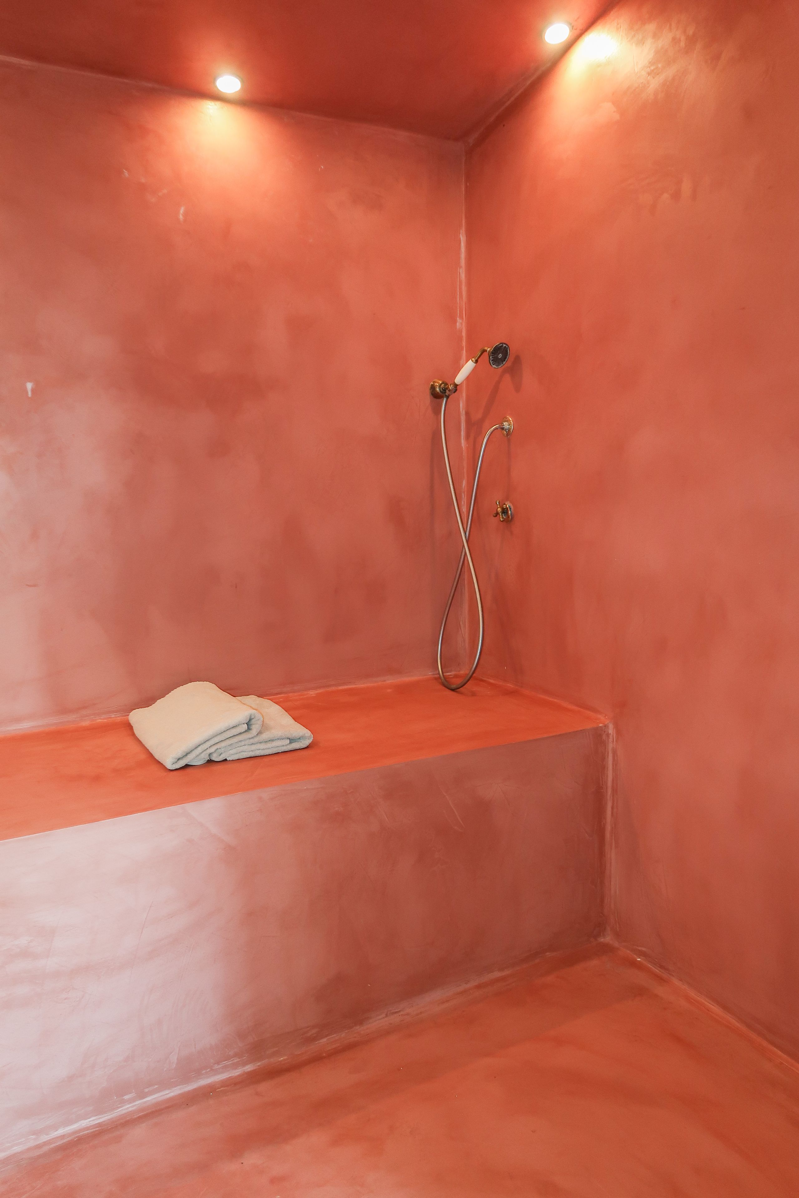 Un petit espace de douche fermé, équipé d’un banc et d’une serviette.