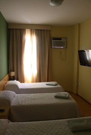 Quarto de hotel com duas camas, uma TV de tela plana na parede e uma janela com cortinas.