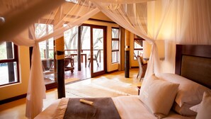 Un dormitorio con una cama grande, dosel y vistas al exterior.