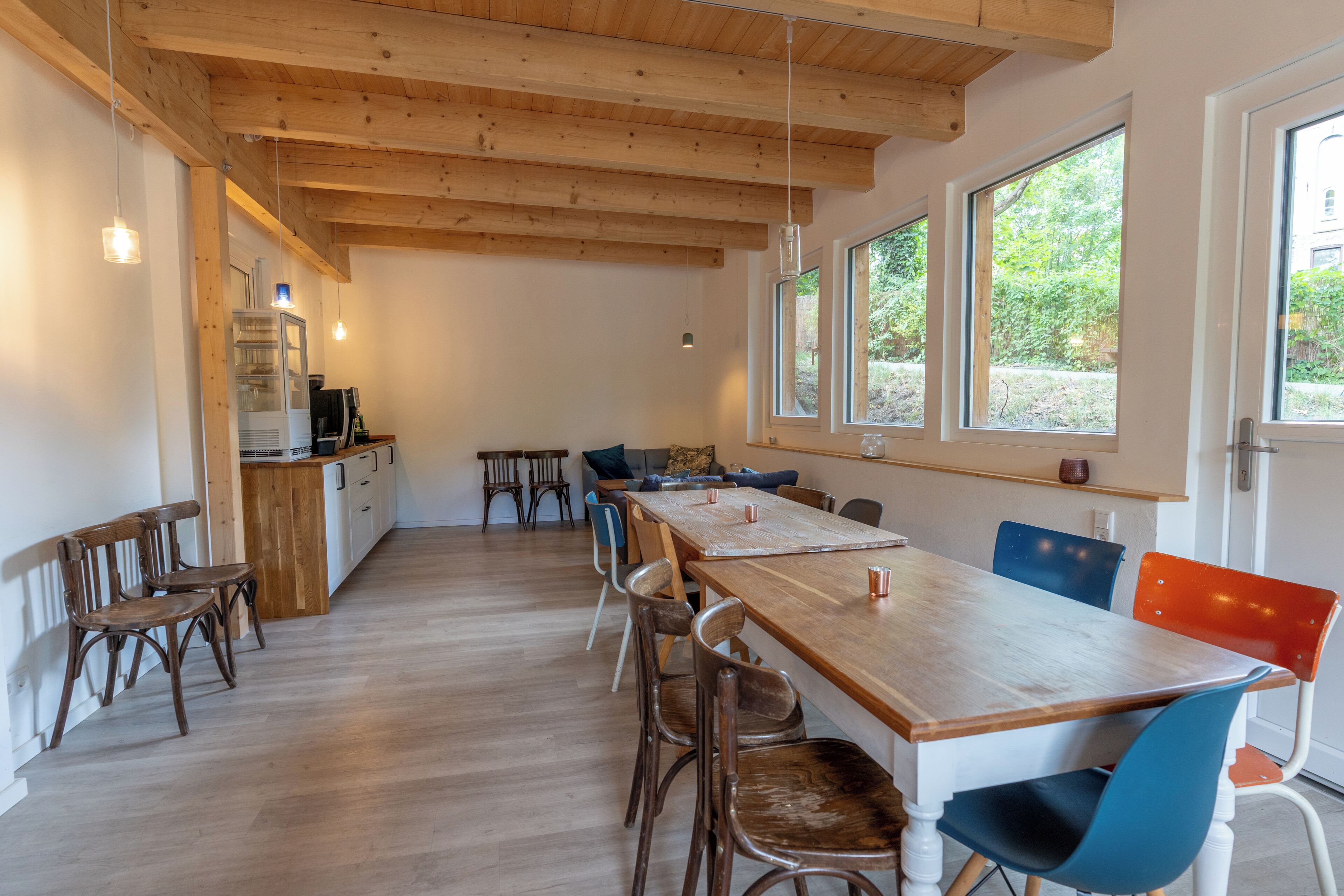 A spacious kitchen with wooden beams, a long table, and chairs.