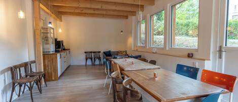 A spacious kitchen with wooden beams, a long table, and chairs.