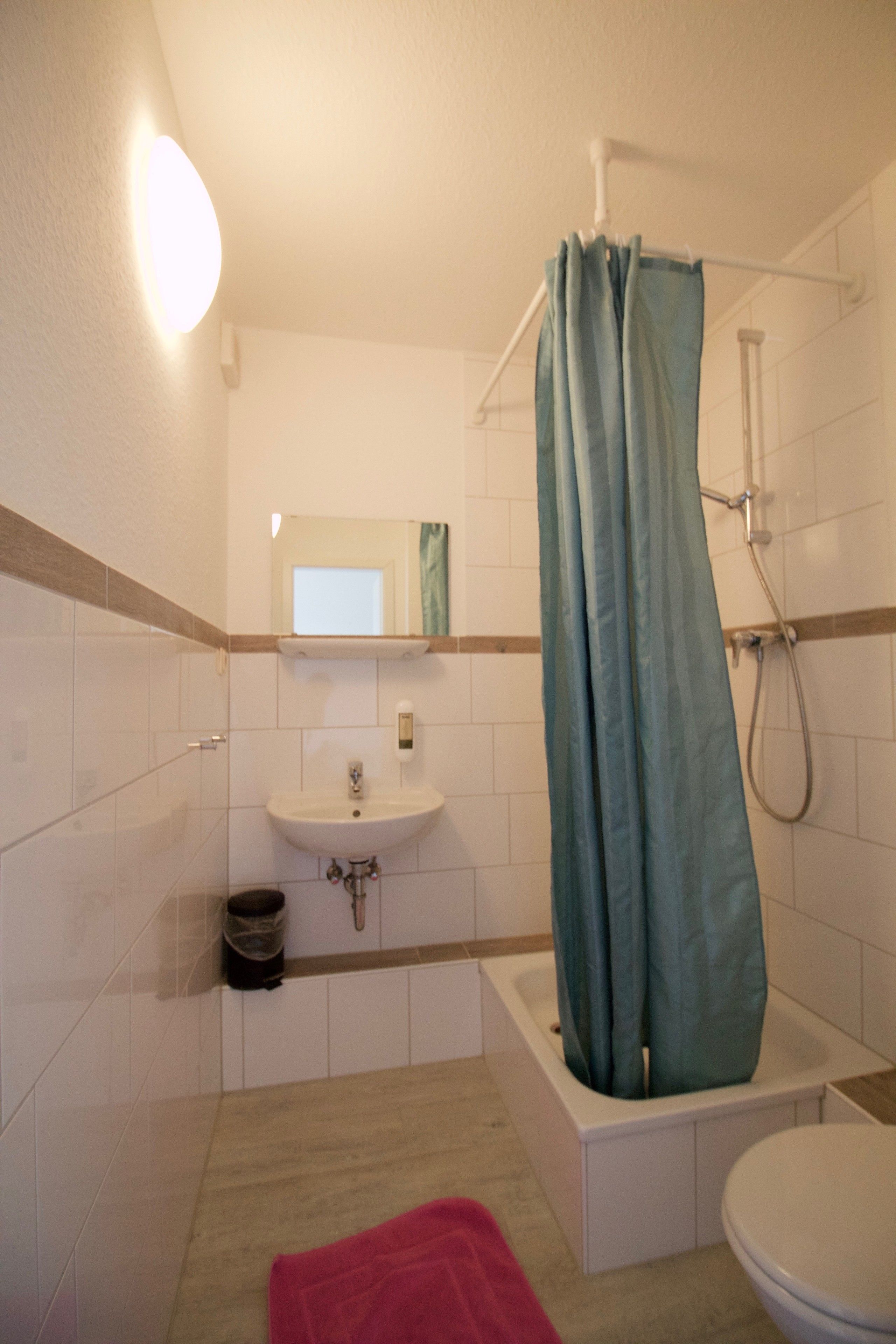 Un baño con lavamanos, espejo, ducha e inodoro.