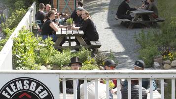 A hostel with outdoor seating and a red van in the background.