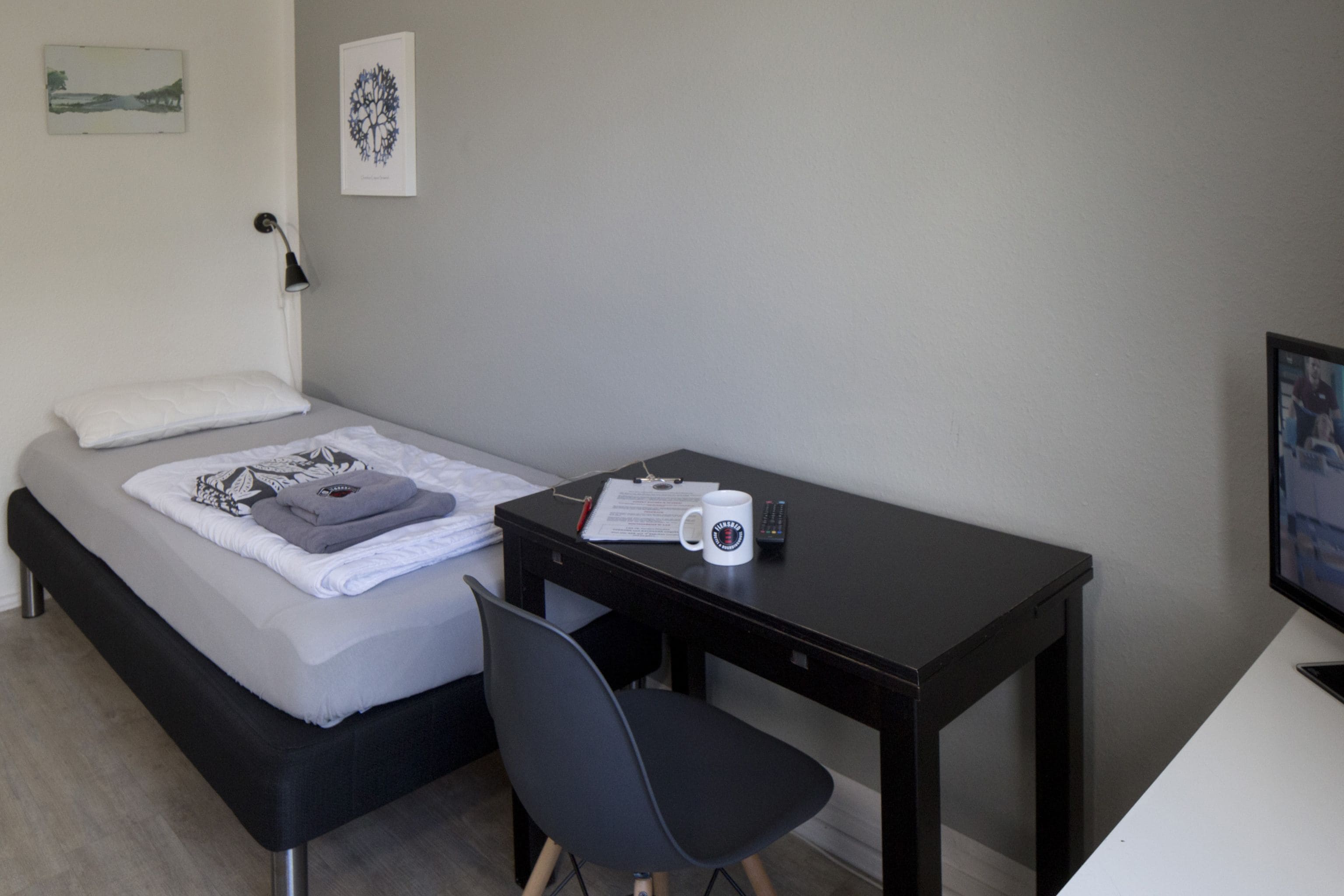 Un dormitorio ordenado con cama, escritorio y silla.
