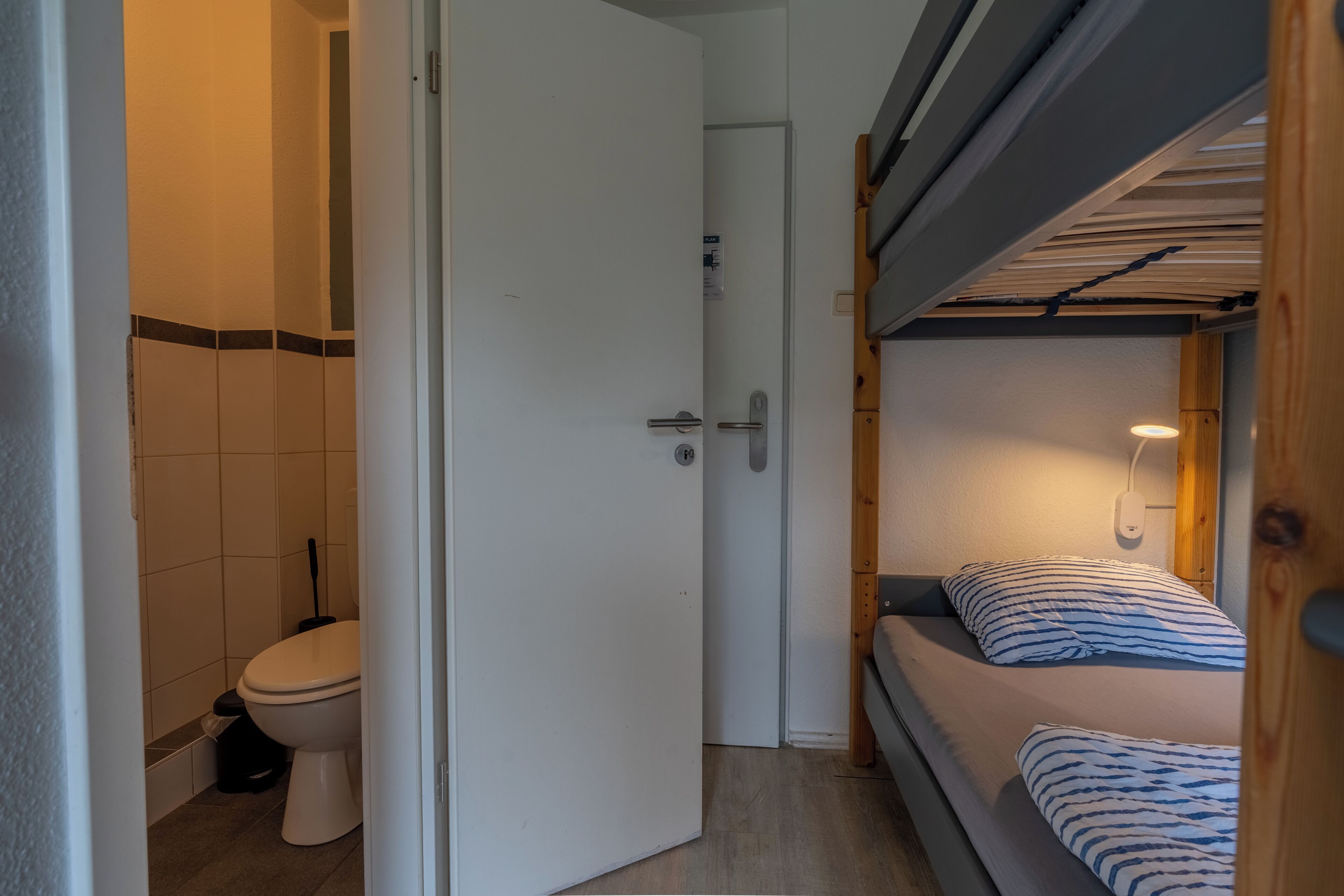Ein kleines Zimmer mit einer Etagenbett, einer Toilette und einer Dusche.