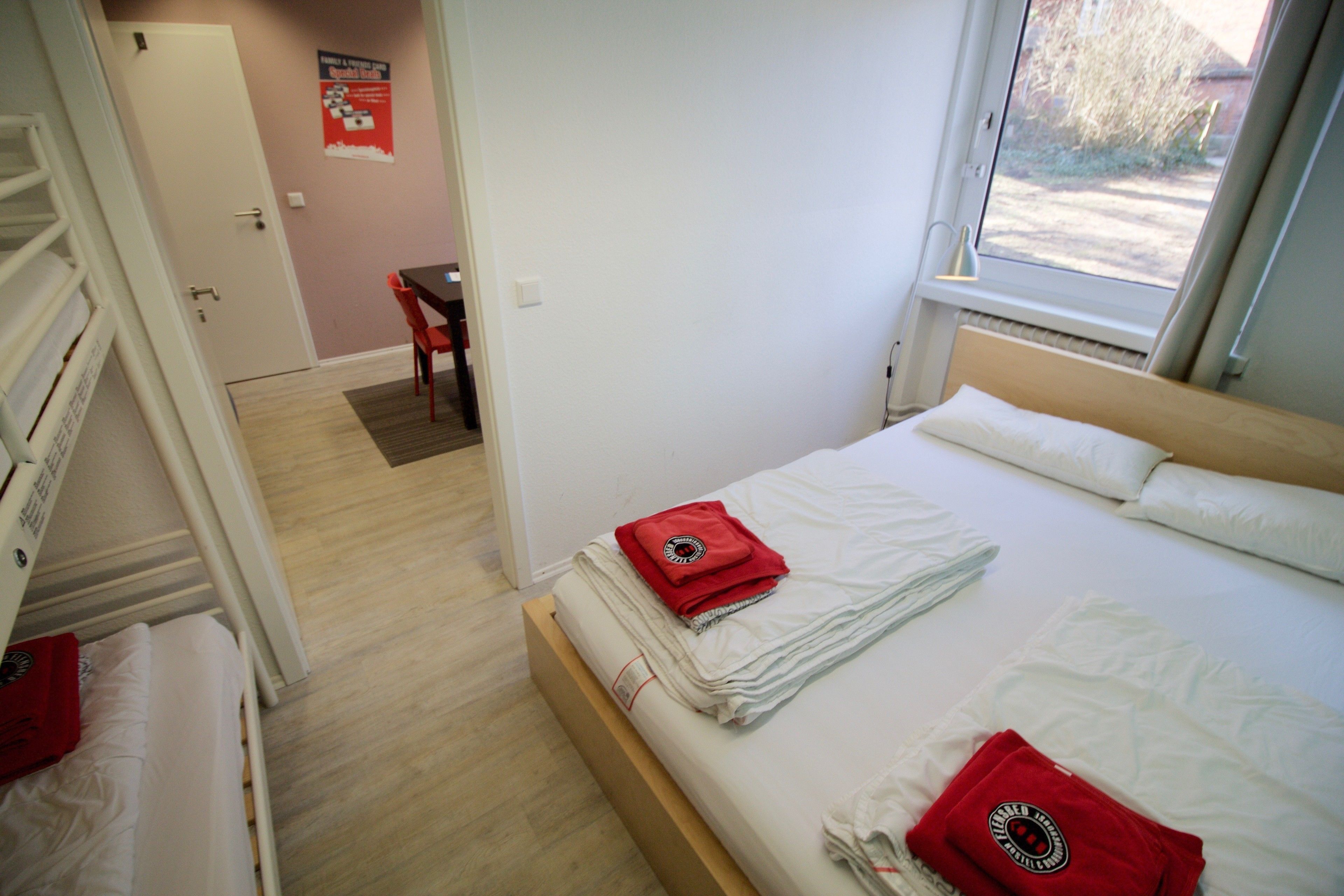 Een slaapkamer met een bed, een bureau en een stoel. Er is een raam dat natuurlijk licht binnenlaat.