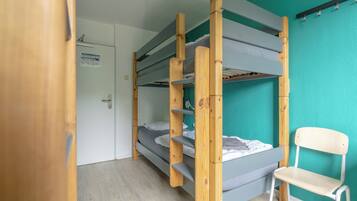 Habitación con literas, una escalera de madera, una silla blanca y pared color aguamarina.
