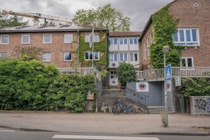 A multi-story building with a brick facade, a staircase leading to the entrance, and a bicycle parked outside. - Flensbed Hotel & Hostel (Flensburg)