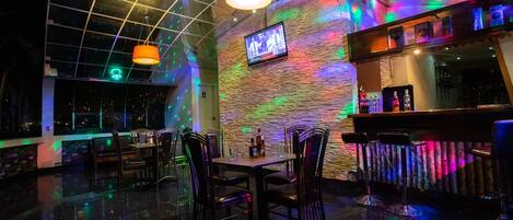 A bar area with a stone wall, multiple hanging lamps, and a bar counter with bottles.