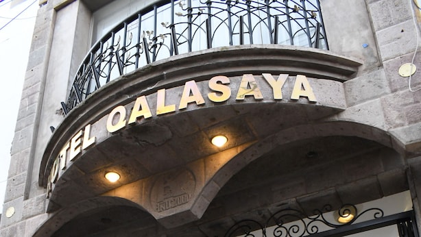 La entrada del Hotel Qalasaya, con fachada de piedra y balcón de hierro forjado.