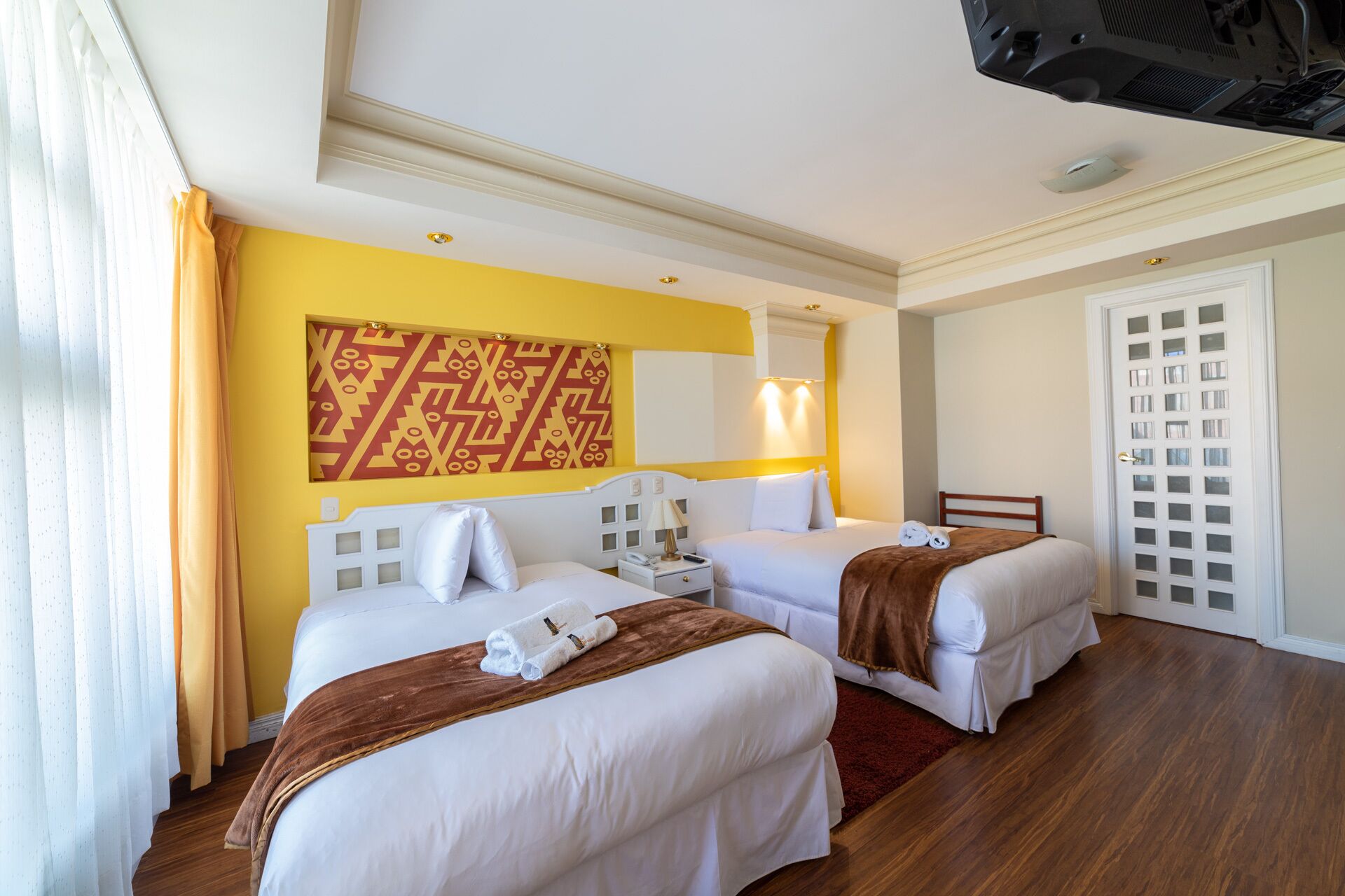 Habitación de hotel con dos camas, un espejo grande y un adorno en la pared.