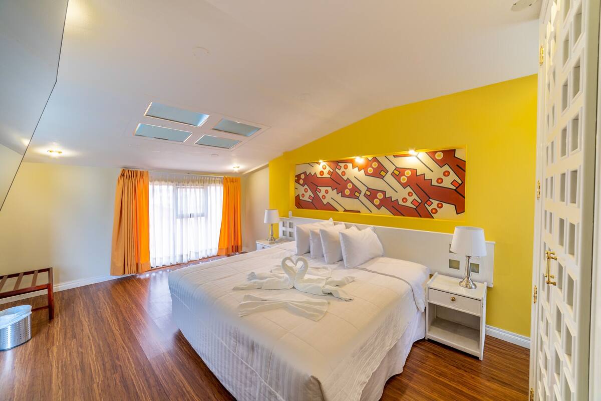 Ein Hotelzimmer mit einem großen Bett, einem Nachttisch, einer Wandlampe und einem dekorativen Wandbild.
