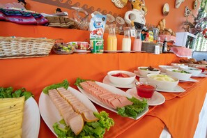Una mesa de buffet con diversos alimentos, como carnes cortadas, ensaladas y bebidas.